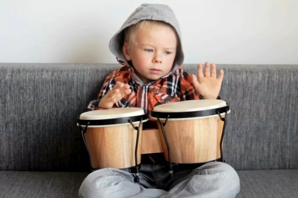 a young child playing with bongos
