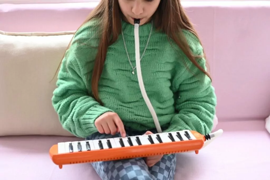 A child playing with a melodica