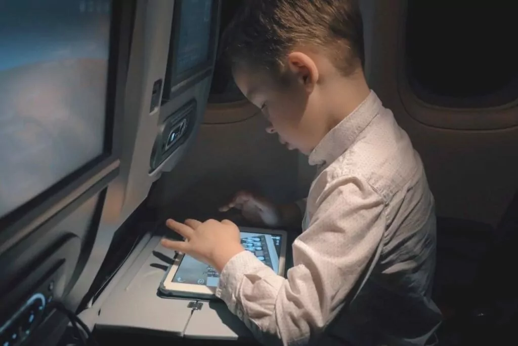 Young boy using a tablet while on an airplane